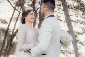 Romantic forest wedding portrait with pine trees in soft lighting.