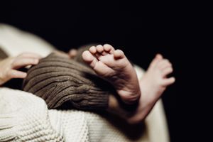 Close up of tiny baby feet and toes on white knitted blanket.