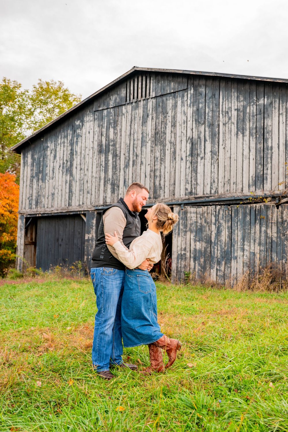 A series of romantic poses in front of a rustic weathered barn during an autumn photoshoot.