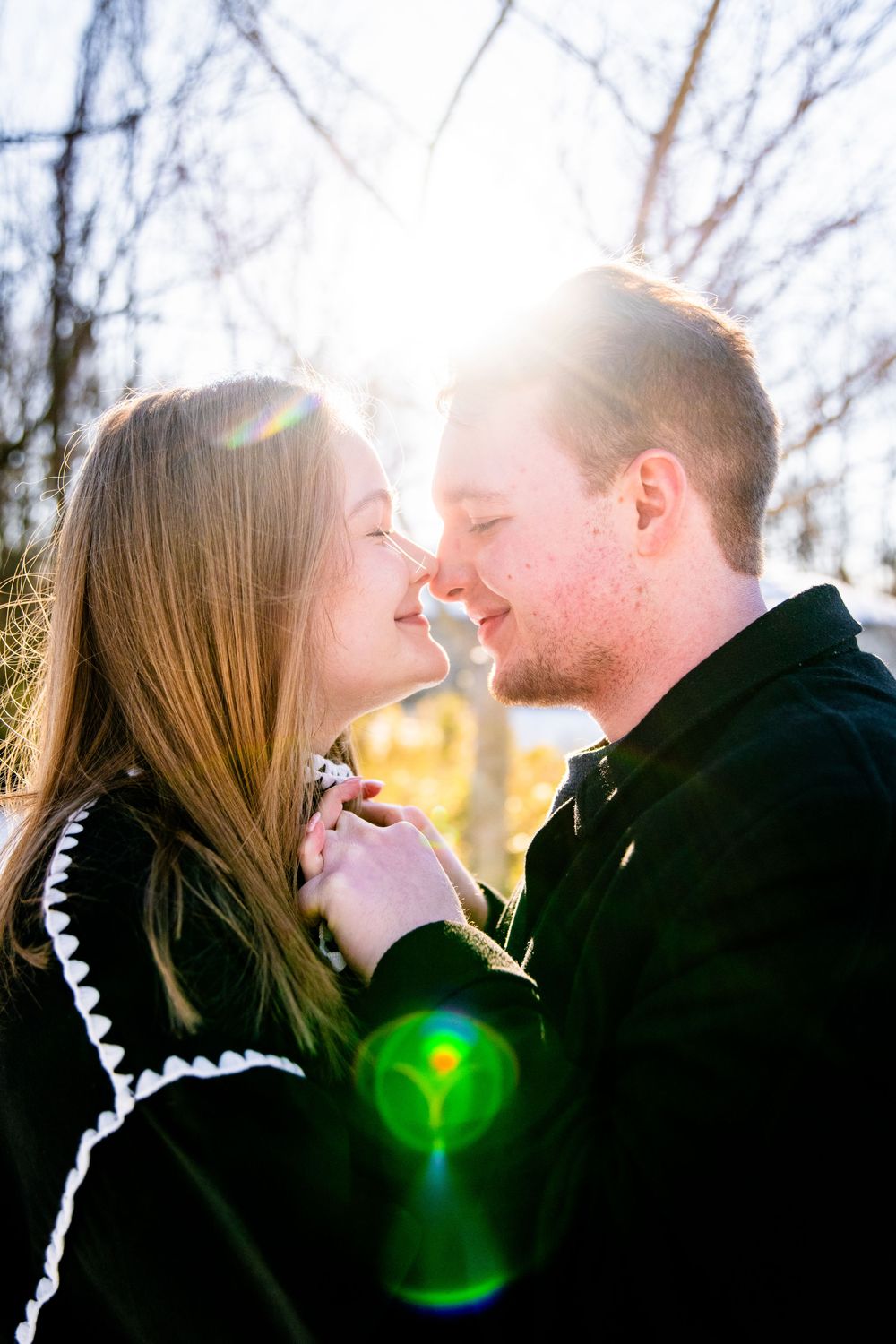 Romantic silhouette of a couple sharing intimate moments in nature with sunlight creating lens flare effects.