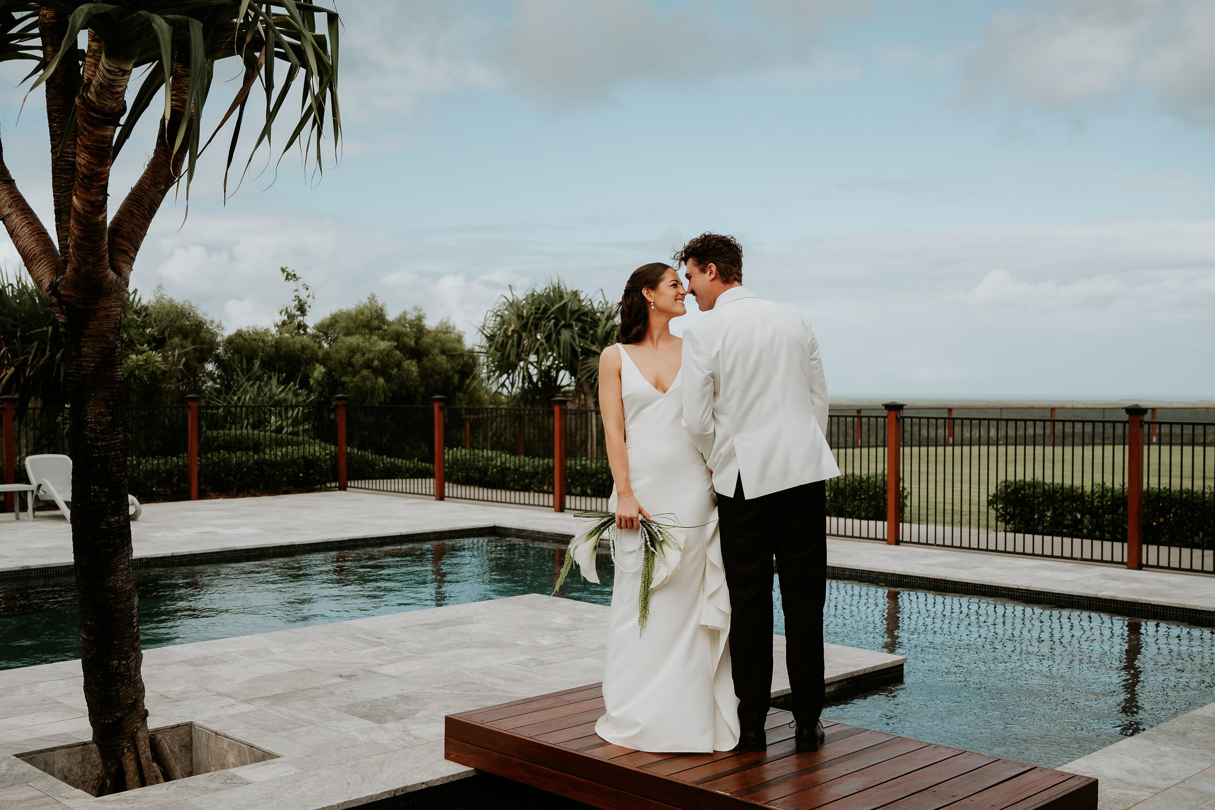 Couple shares romantic moments by an infinity pool overlooking a scenic tropical landscape at Yeppoon wedding venue.