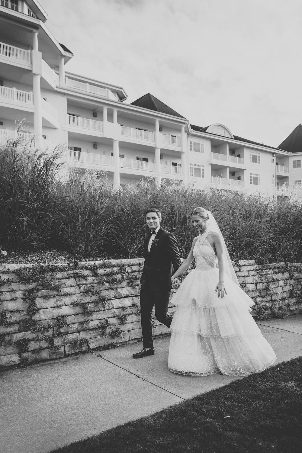 Classic white resort building with stone wall creates elegant wedding venue backdrop.