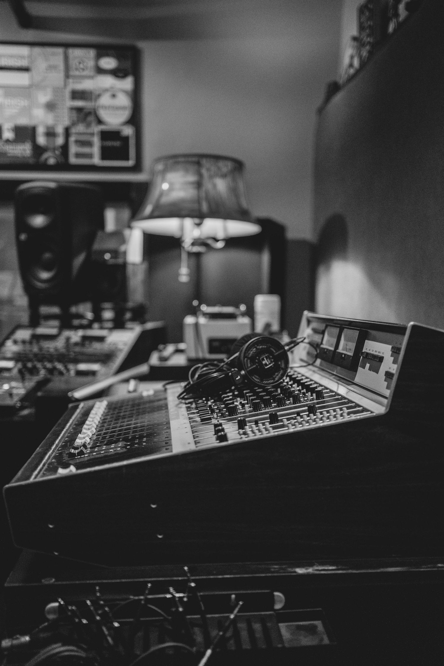 Black and white photo of a professional audio mixing console with headphones in a recording studio.