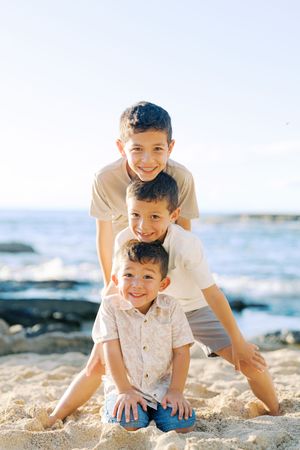 Joyful playtime on a tropical beach with crashing waves and volcanic rocks in the background.