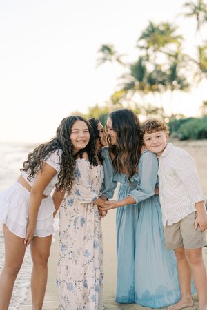 Candid family interactions captured in soft pastel colors on a tropical beach.