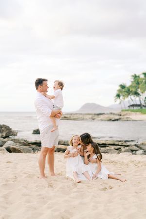 Playful moments captured on a sandy beach with light and airy photography style.