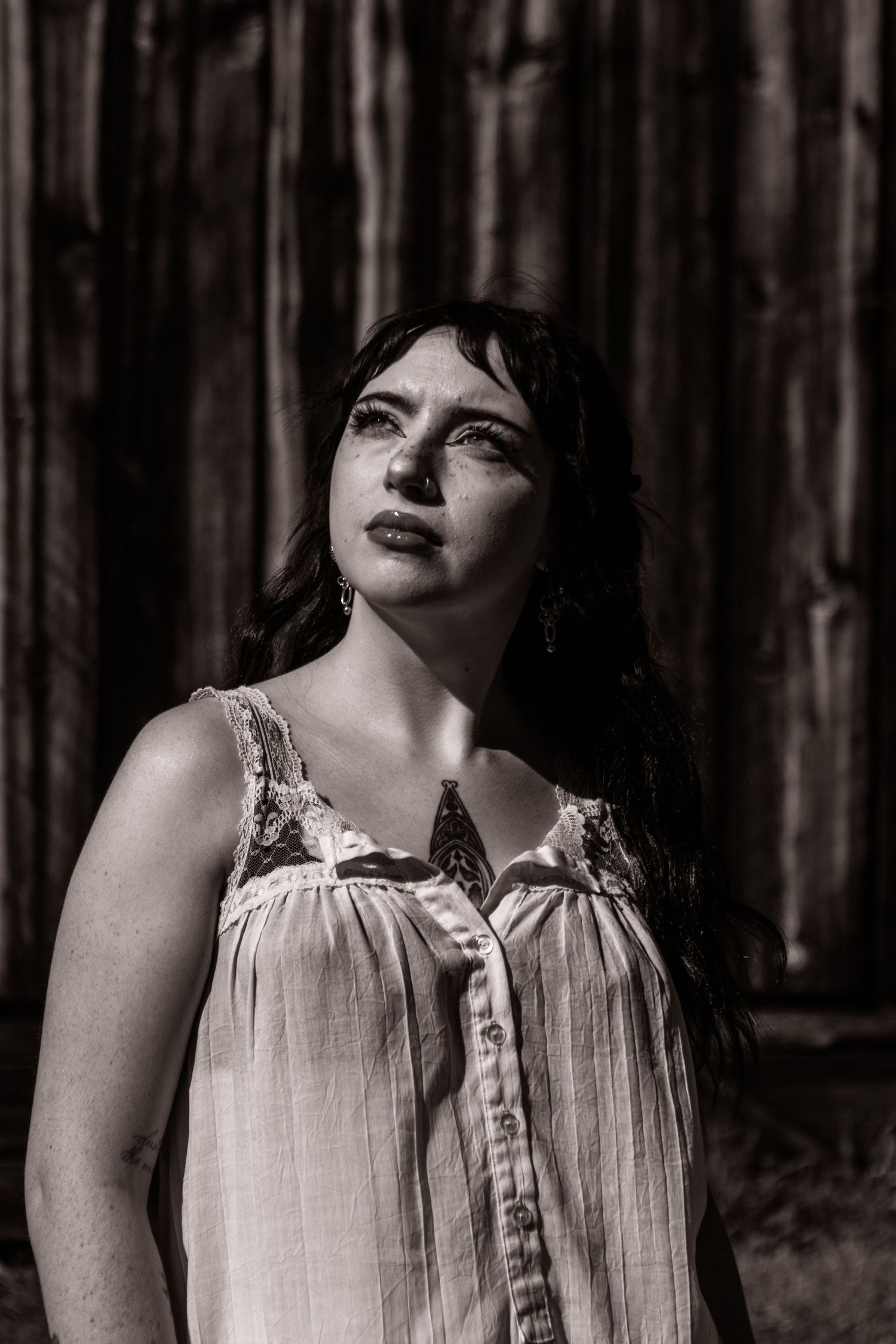 Black and white portrait of a young white model with dark hair and blue eyes in front of a barn. outdoor.