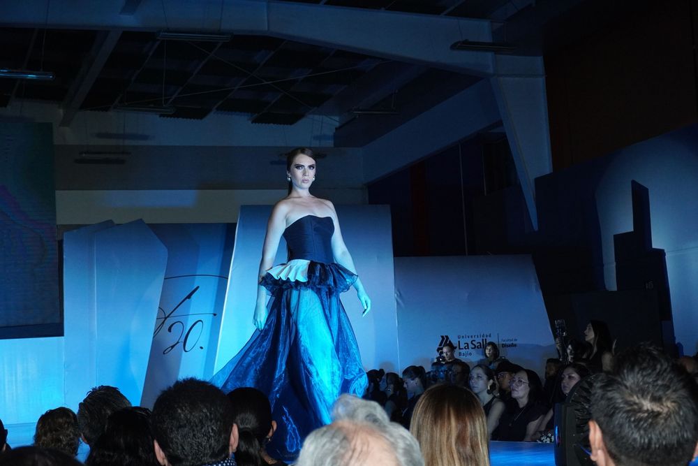 Female model in a stunning blue strapless ball gown walking the runway at a fashion show event.