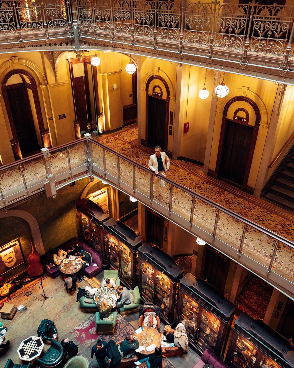 High angle view of an ornate historic theater interior with balconies and patrons seated at round tables below.