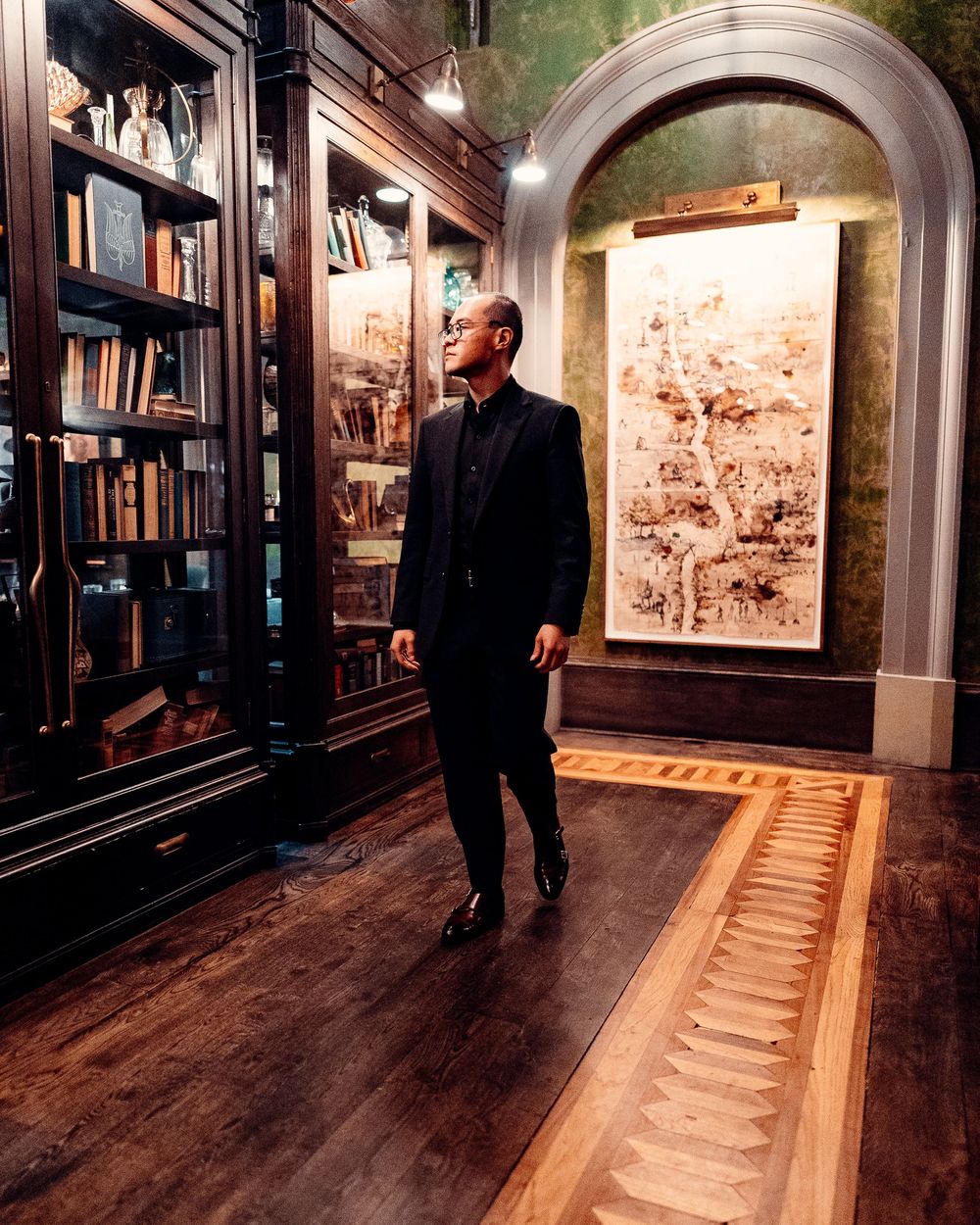 A person walks through a dimly lit museum corridor featuring illuminated wall displays of historical artwork and artifacts.