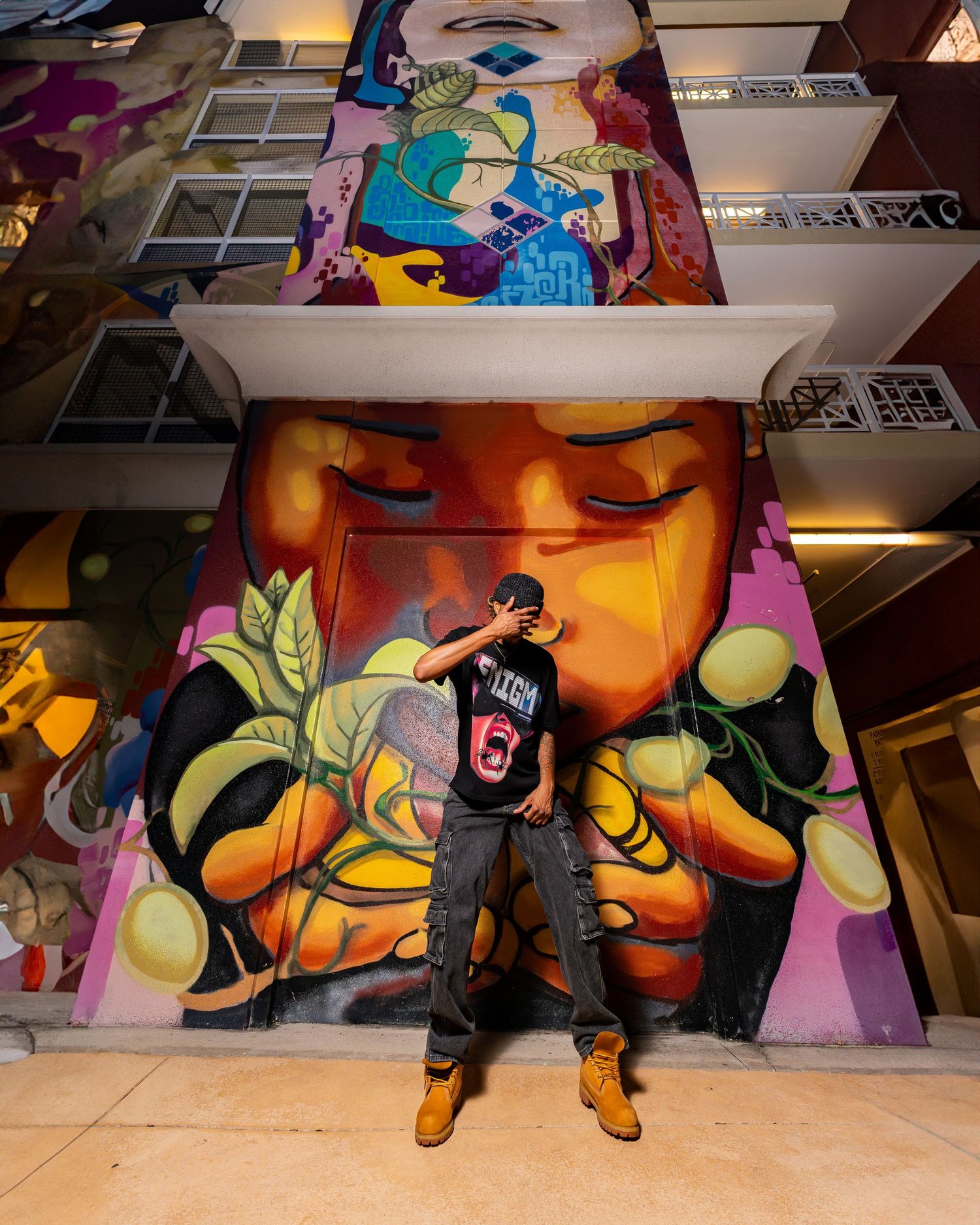 Urban street art scene with colorful graffiti mural and person posing.