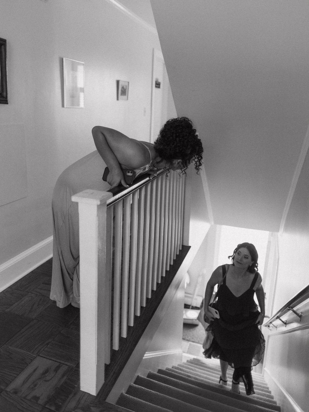 Black and white image of people descending stairs in formal attire.