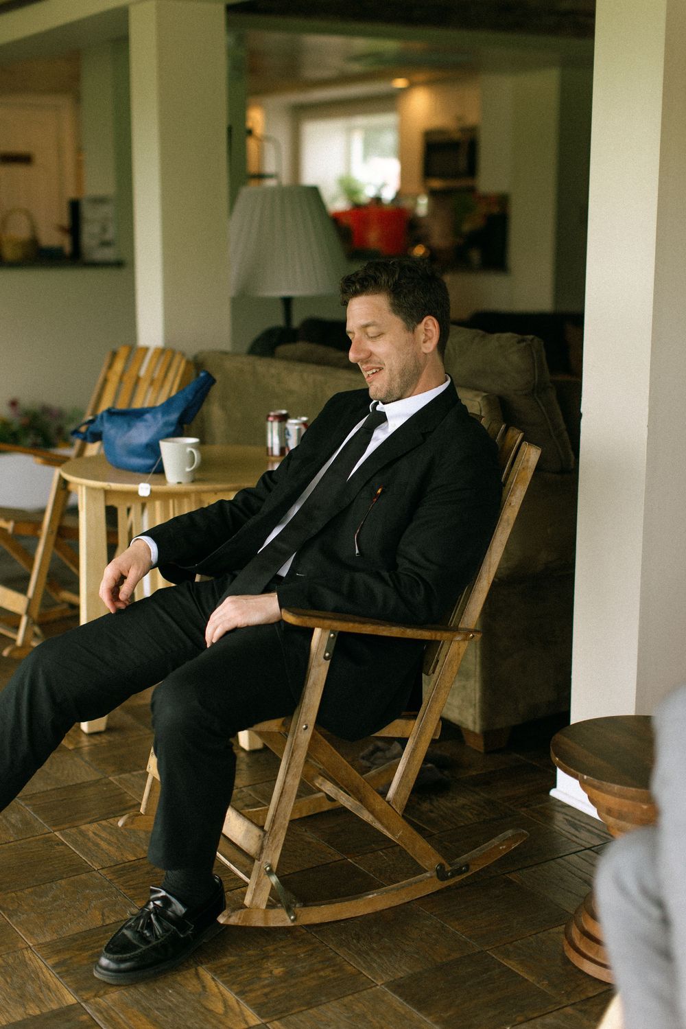 Person in formal suit relaxing in wooden rocking chair.