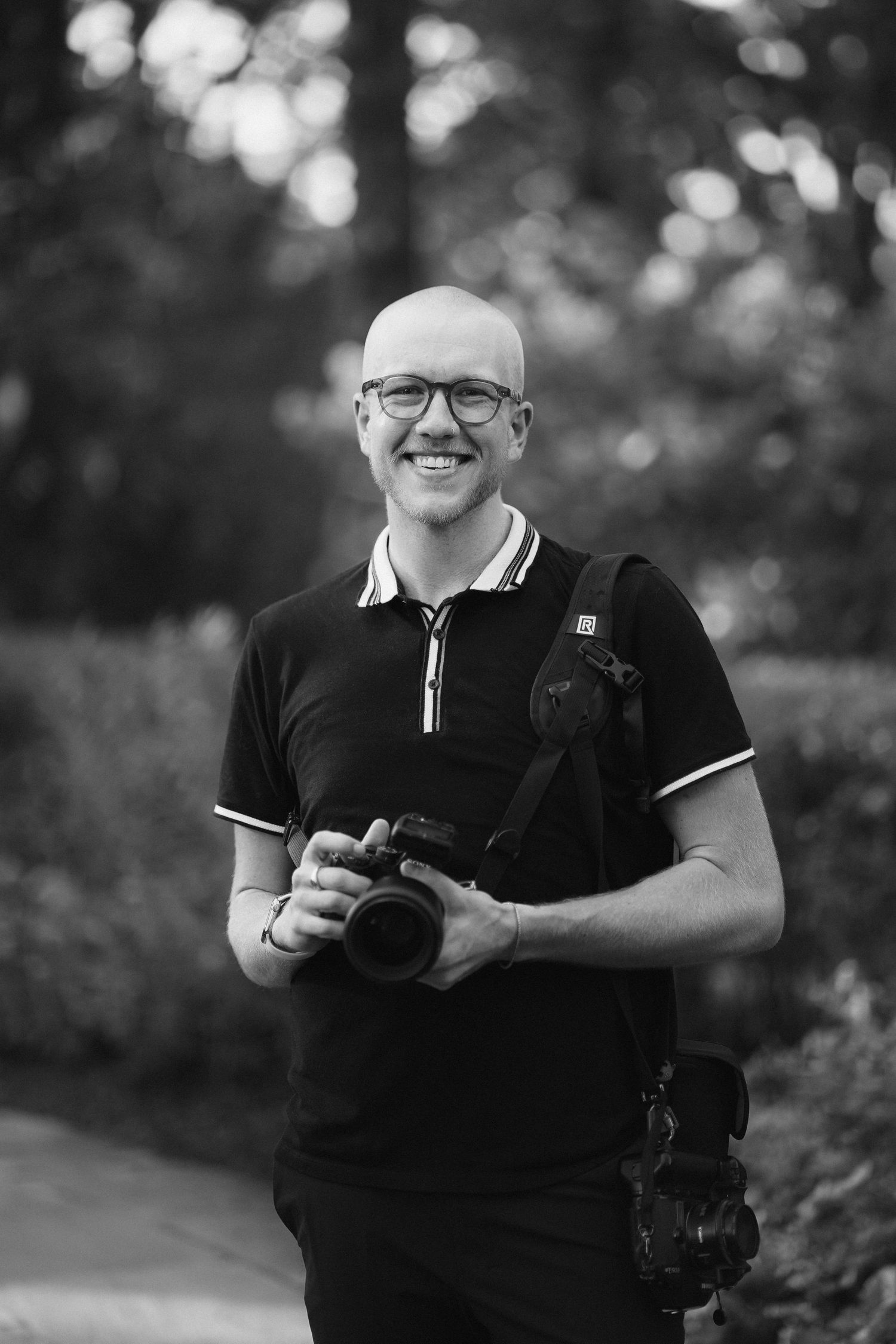 Black and white portrait series of photographer holding camera and smiling.