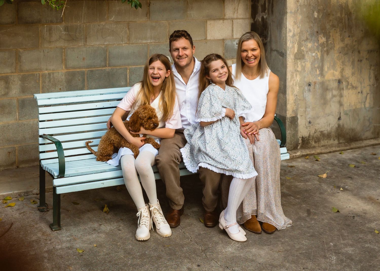 Mother and father smiling at daughter during a family photo shoot in local Ashgrove park