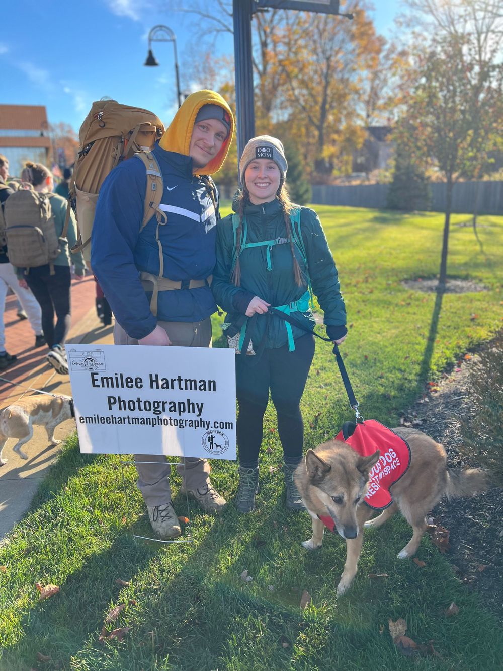 Photography business display at outdoor event with dog wearing red bandana.