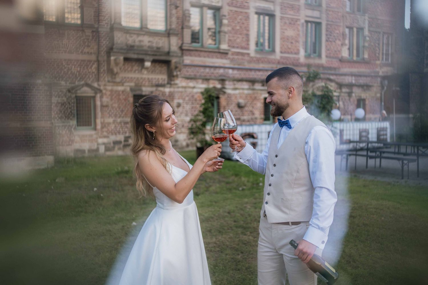 Wedding couple toasting with drinks in garden setting.