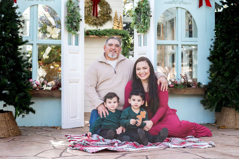 Family sitting on blanket for holiday photo in front of decorated storefront.