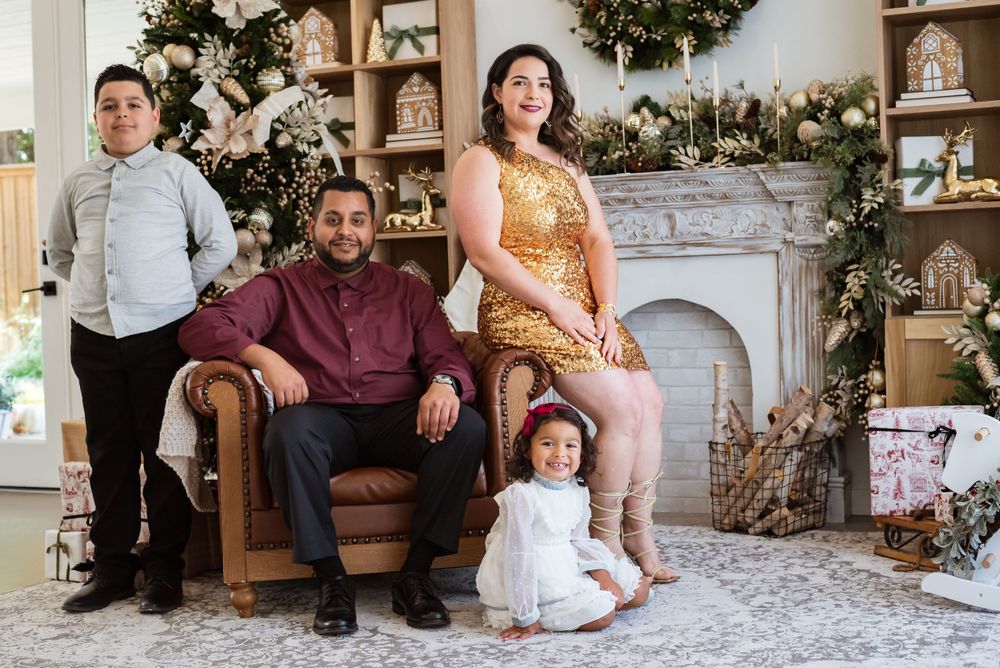 Family holiday portrait in front of decorated fireplace with Christmas decor.