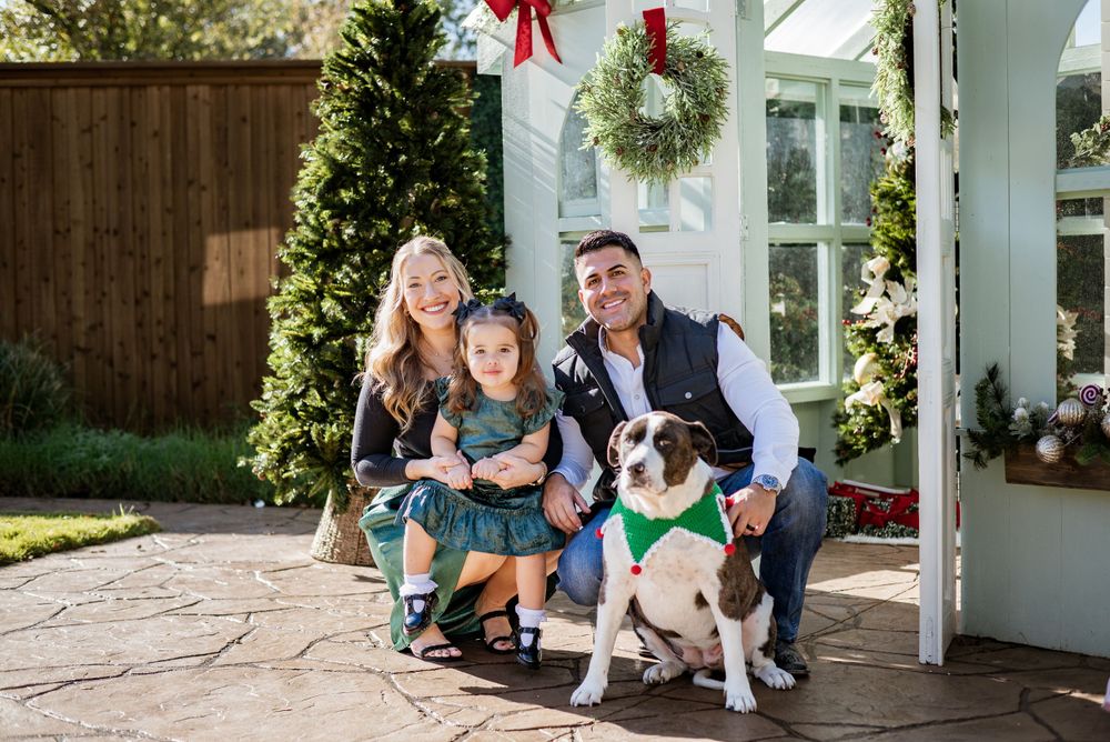 A family poses with their dogs on their decorated porch during the holiday season.