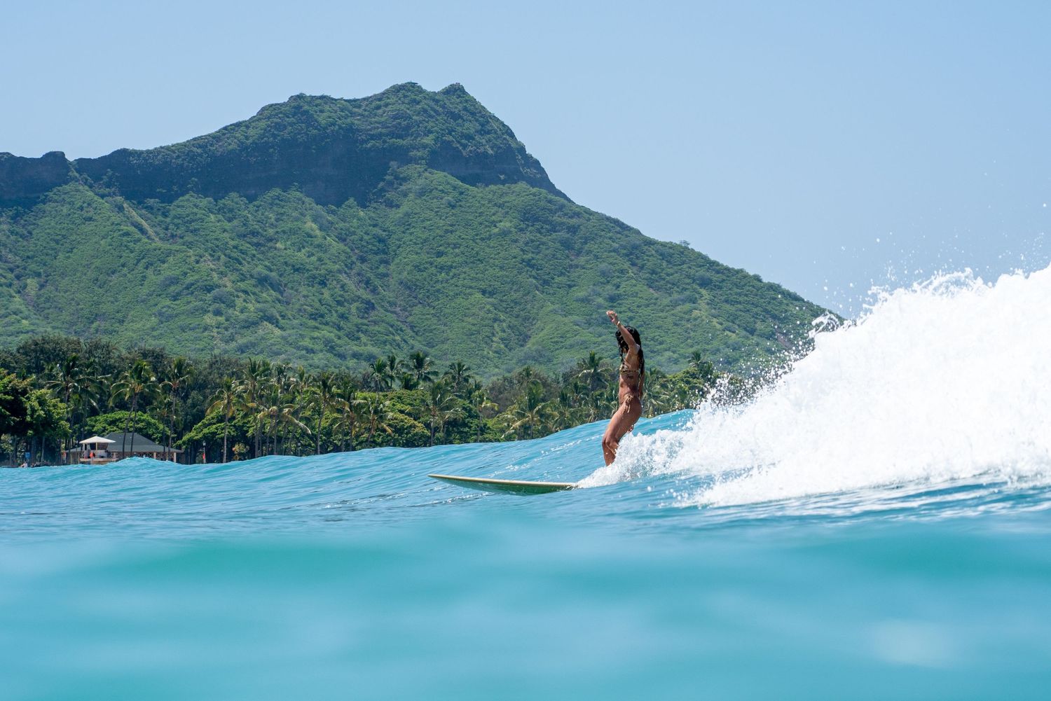 Series of surfing action shots with scenic mountain backdrop in tropical waters.