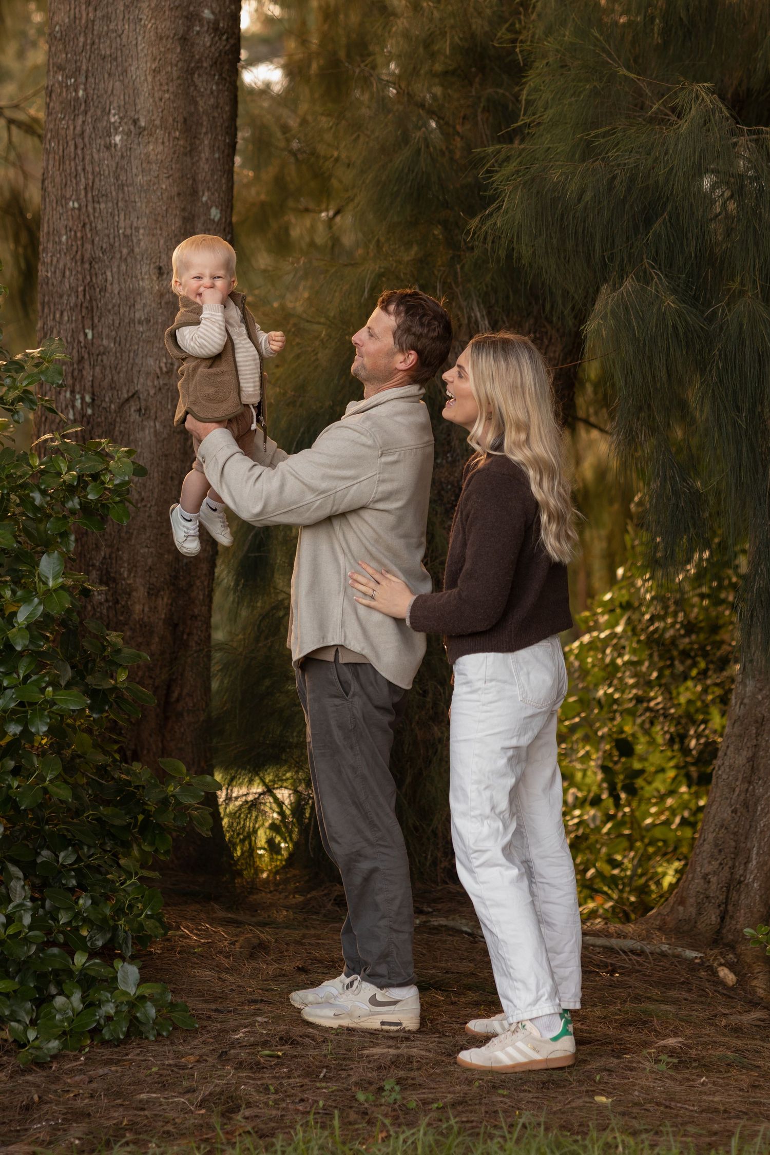 Family portrait taken in a Forest. 3 children and their parents stand together smiling. Sunlight through trees. Family photoshoot. CL Photo