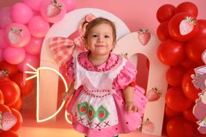 Pink and red balloon arch with strawberry decorations against pink backdrop.
