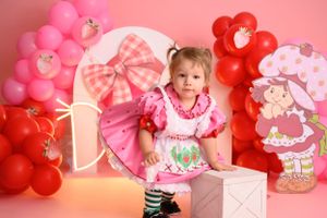 Strawberry-themed party setup with pink and red balloons and decorative elements.