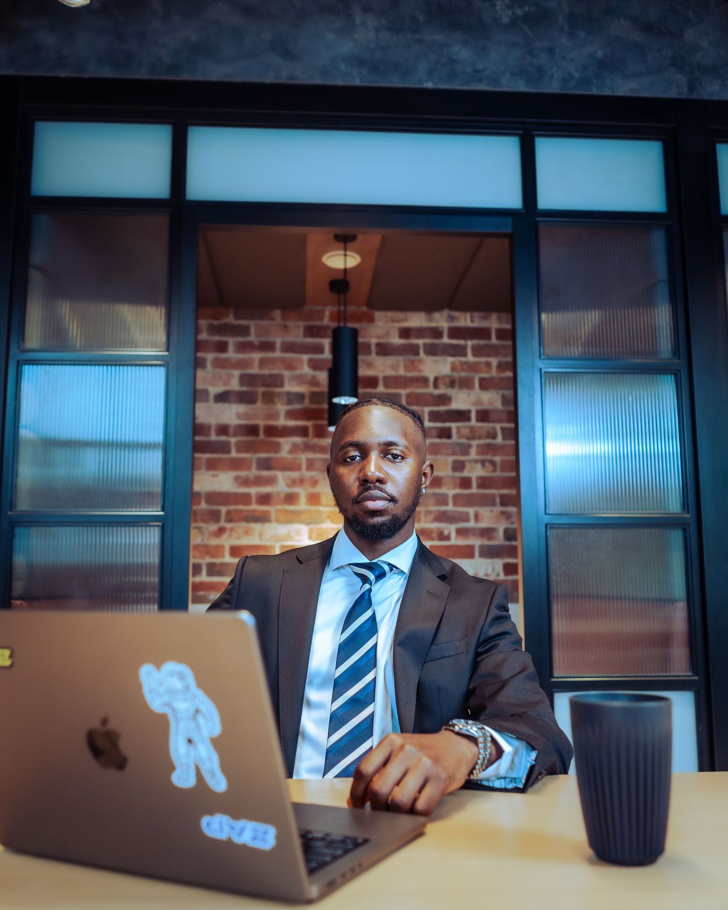 Professional man in a suit and tie sitting at a desk with an open MacBook laptop.