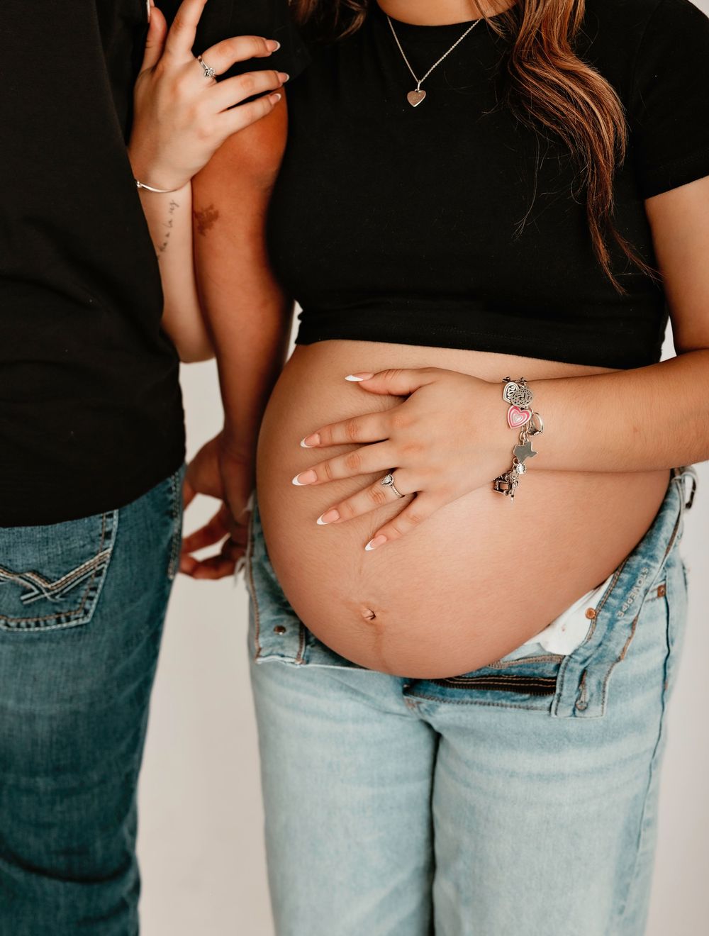Maternity session with a woman with a hand on her pregnant belly and the other arm holding her partners arm in Lake Jackson TX