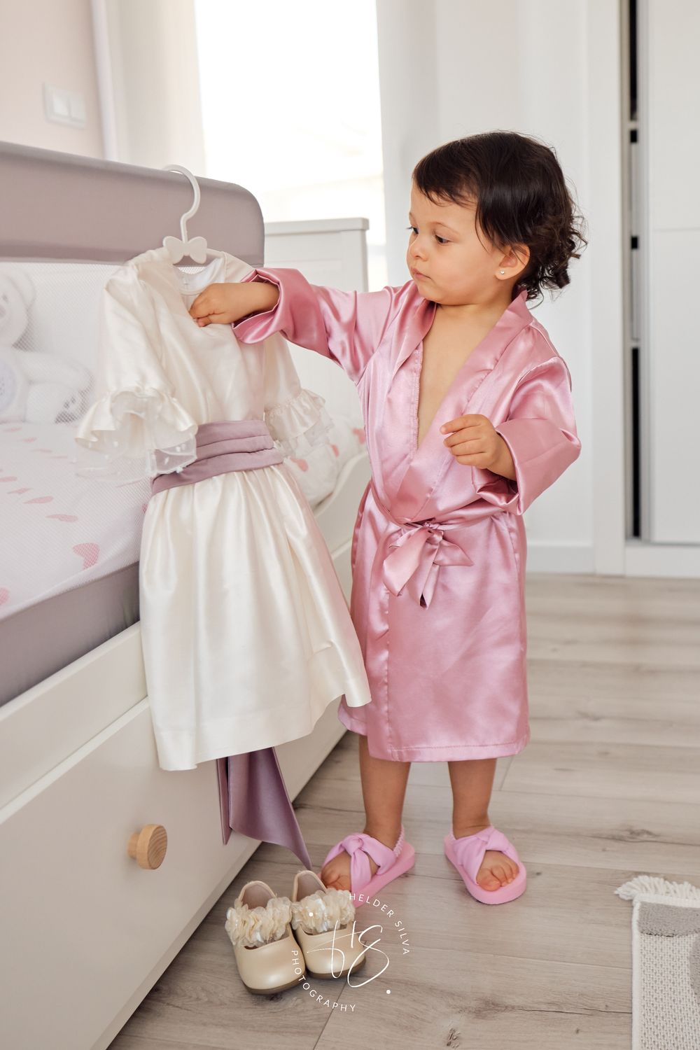 Bebe com robe a olhar para vestido de batizado
