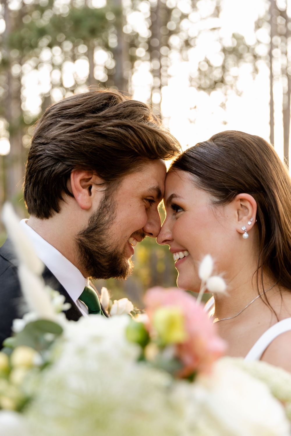 Intimate close-up of a romantic moment between newlyweds with florals in foreground.