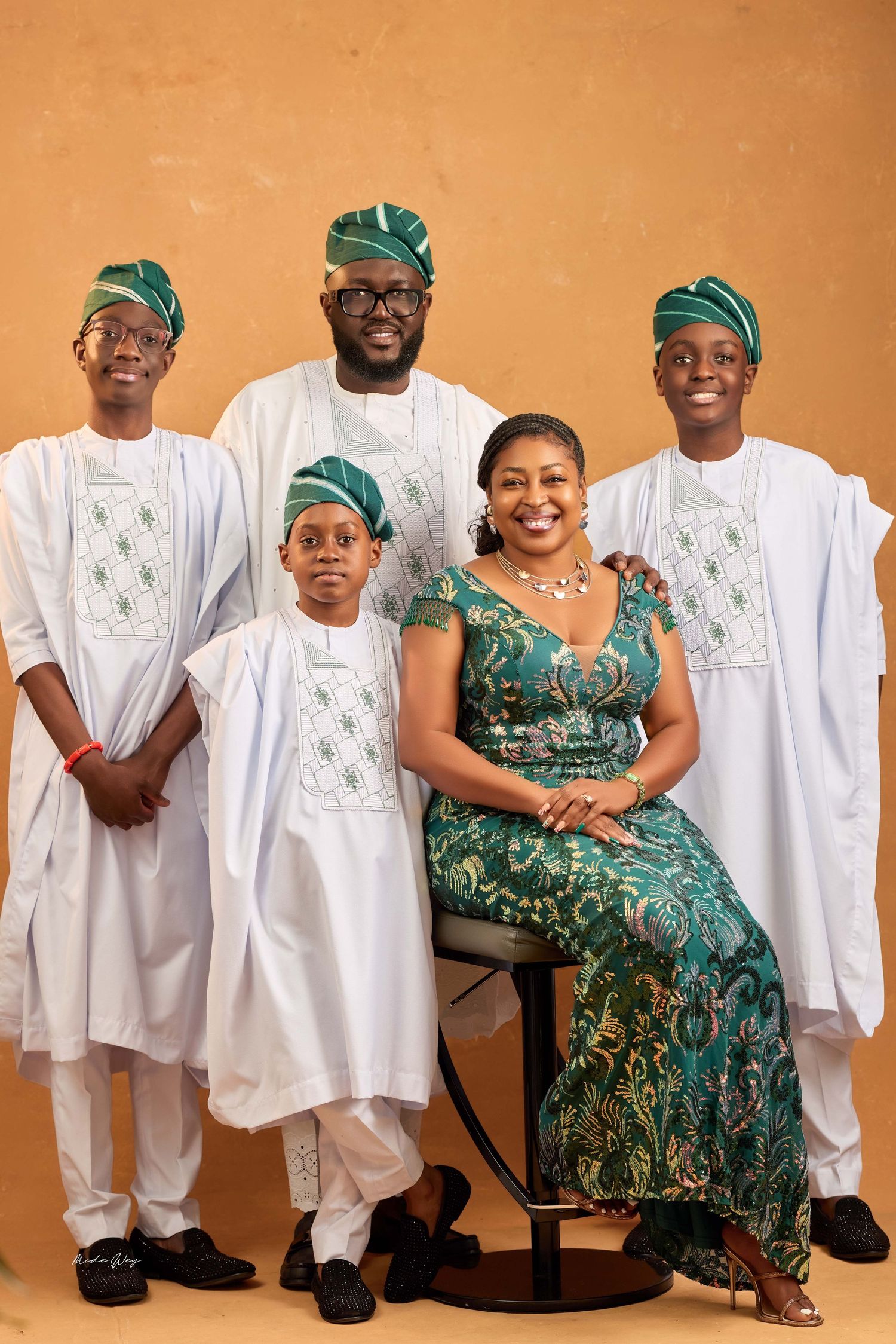 A family portrait series showing members in coordinated white and green traditional Nigerian attire against a warm brown backdrop.