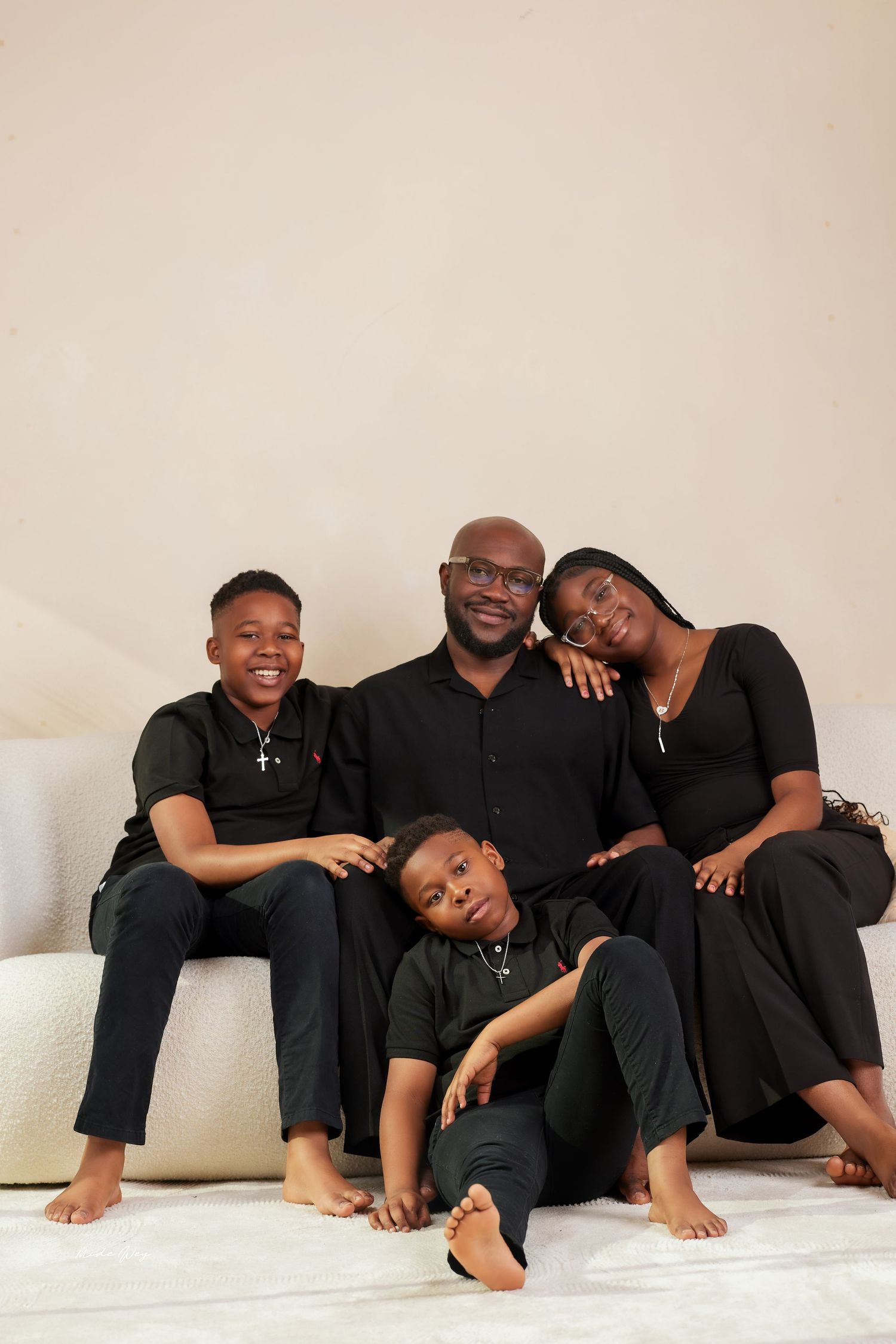 A series of black and white photographs showing a family in matching black outfits posing playfully on a light background.