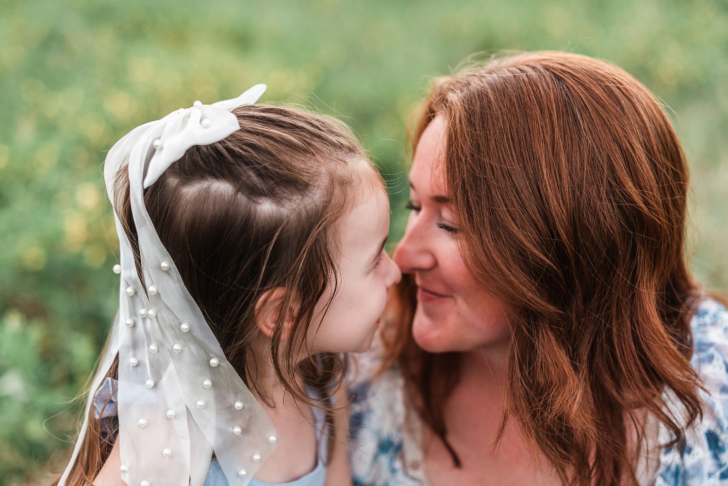 A mom and daughter share a sweet moment in a garden setting.