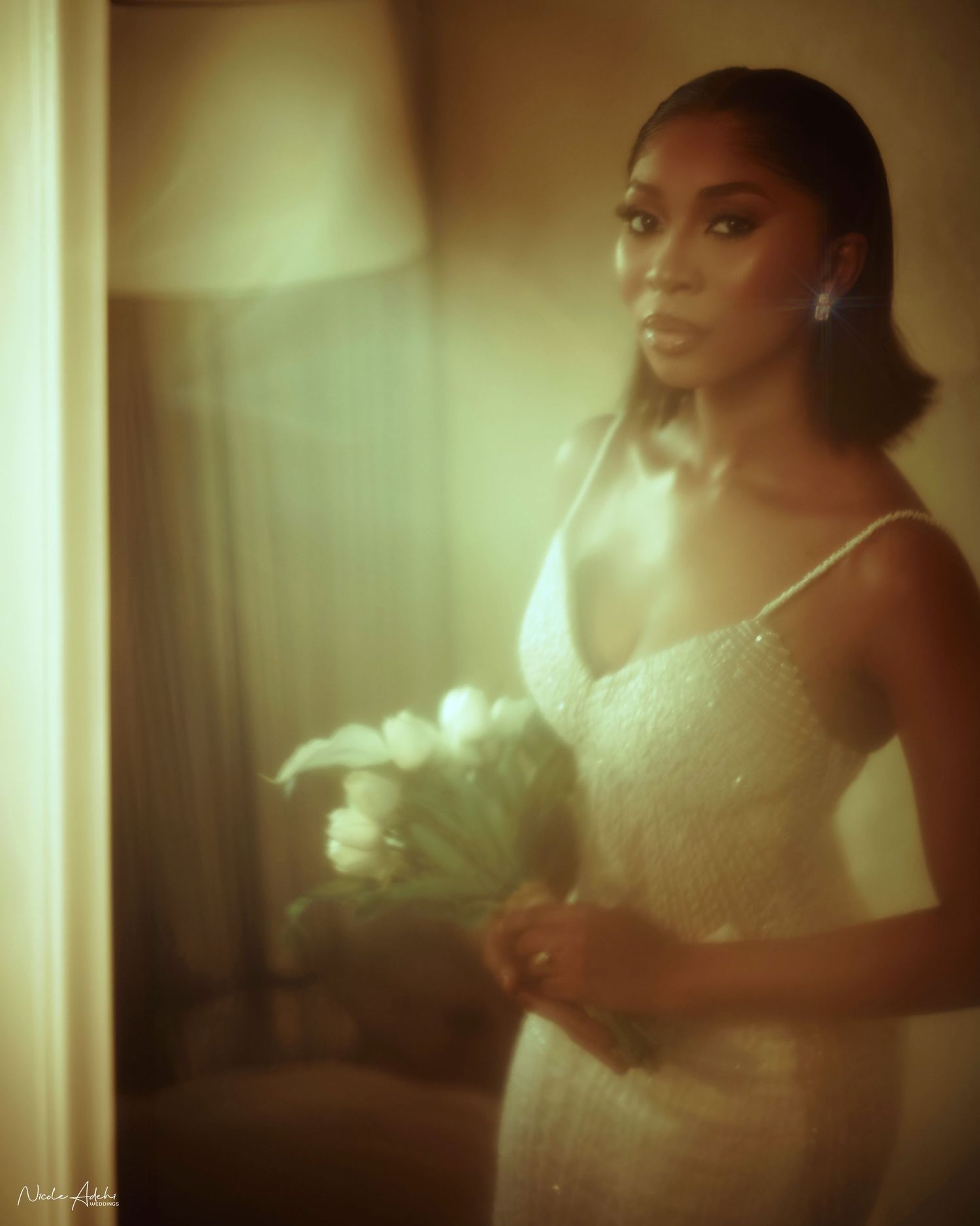 Fine art photo of bride sitting in vintage chair with bouquet on lap