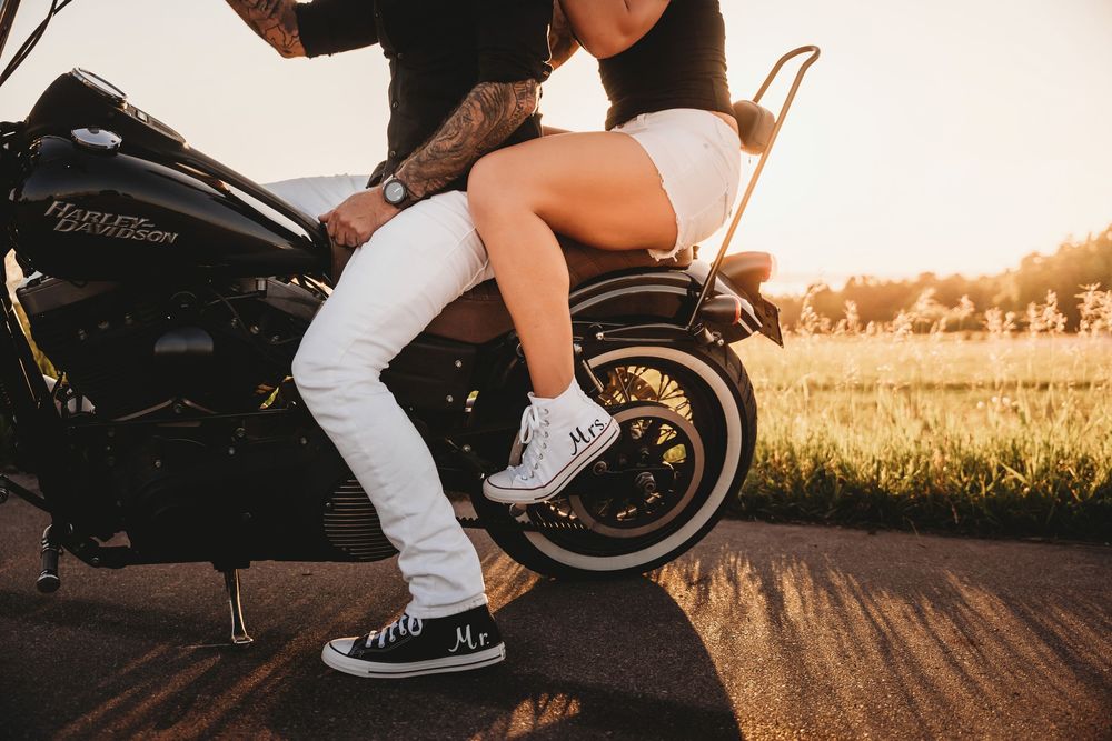Motorcycle and riders photographed from ground level during sunset with warm golden lighting.