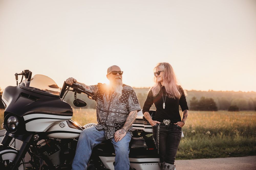 Group gathered around motorcycles at sunset in a rural field setting.