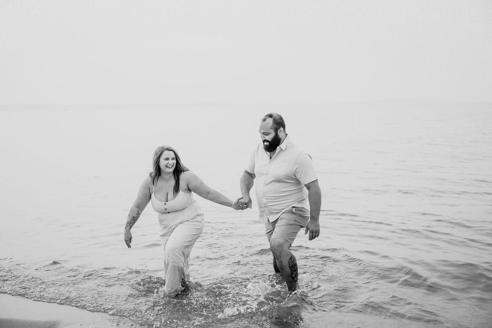 A black and white photo sequence shows a couple playfully splashing and falling into the ocean water at the beach.