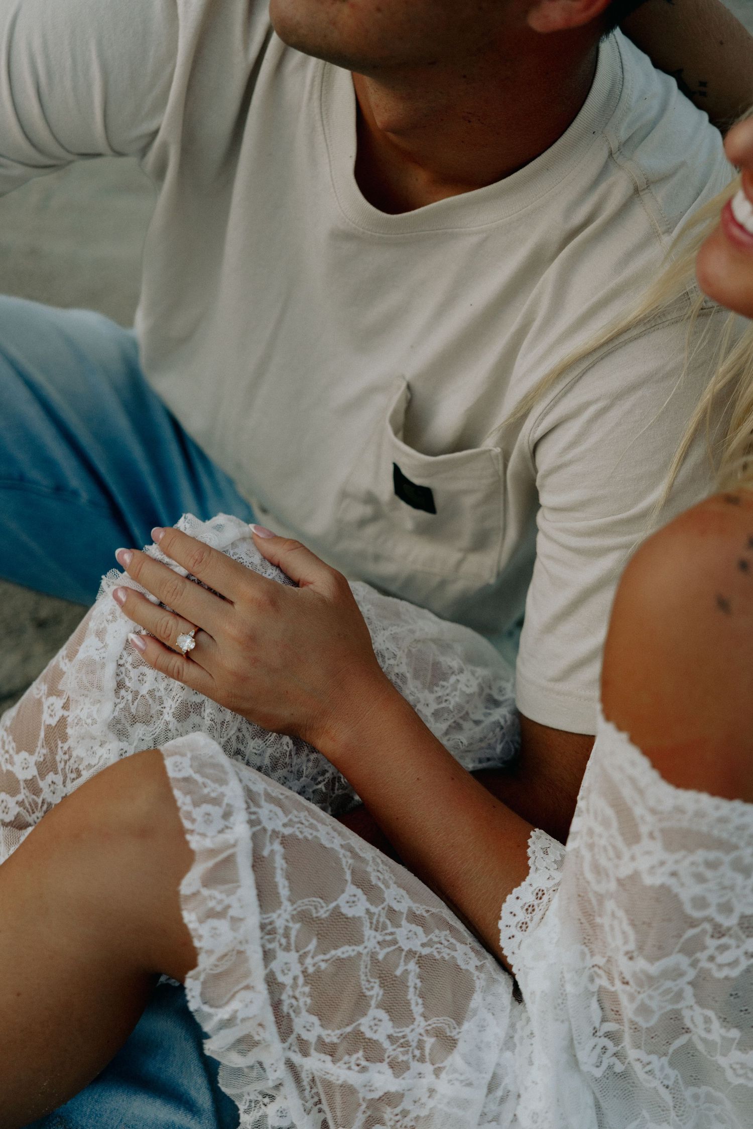 Close-up of woman's engagement ring while sitting with partner outdoors.
