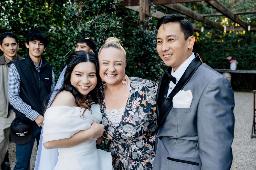 Wedding guests and bridal party gather for outdoor group photos at a garden venue.