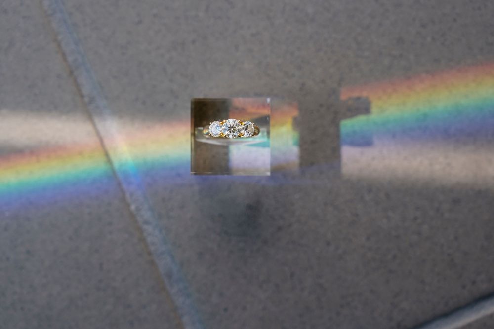 A series of prisms creating rainbow light refractions against a dark background.