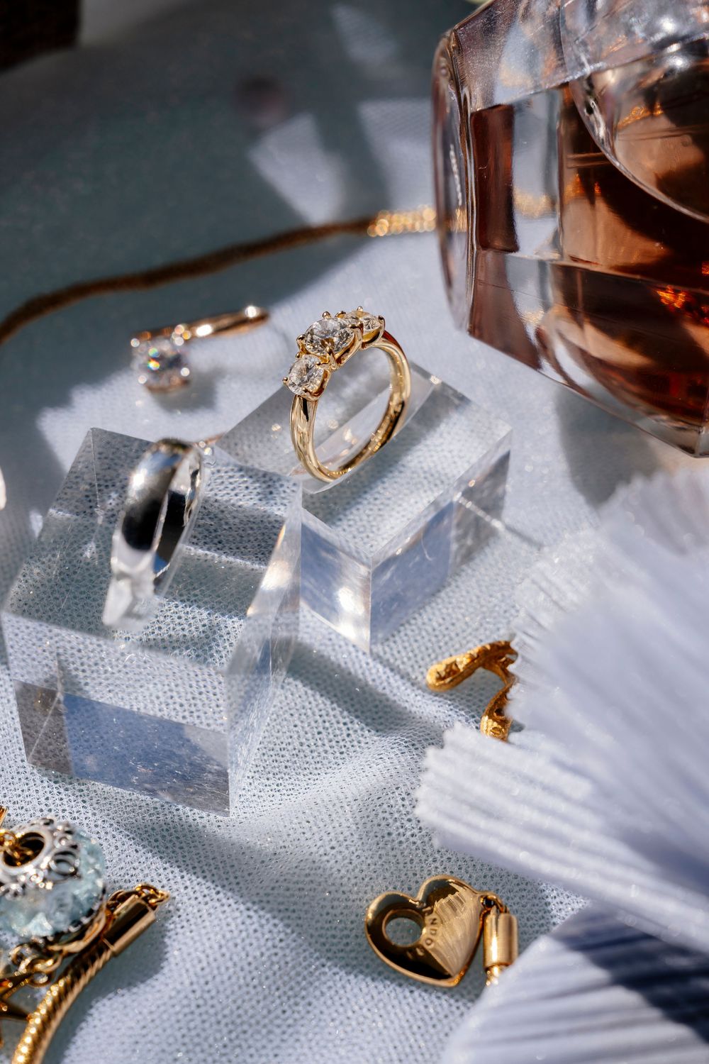 Wedding accessories and jewelry arranged on a textured silver surface with dramatic lighting and shadows.