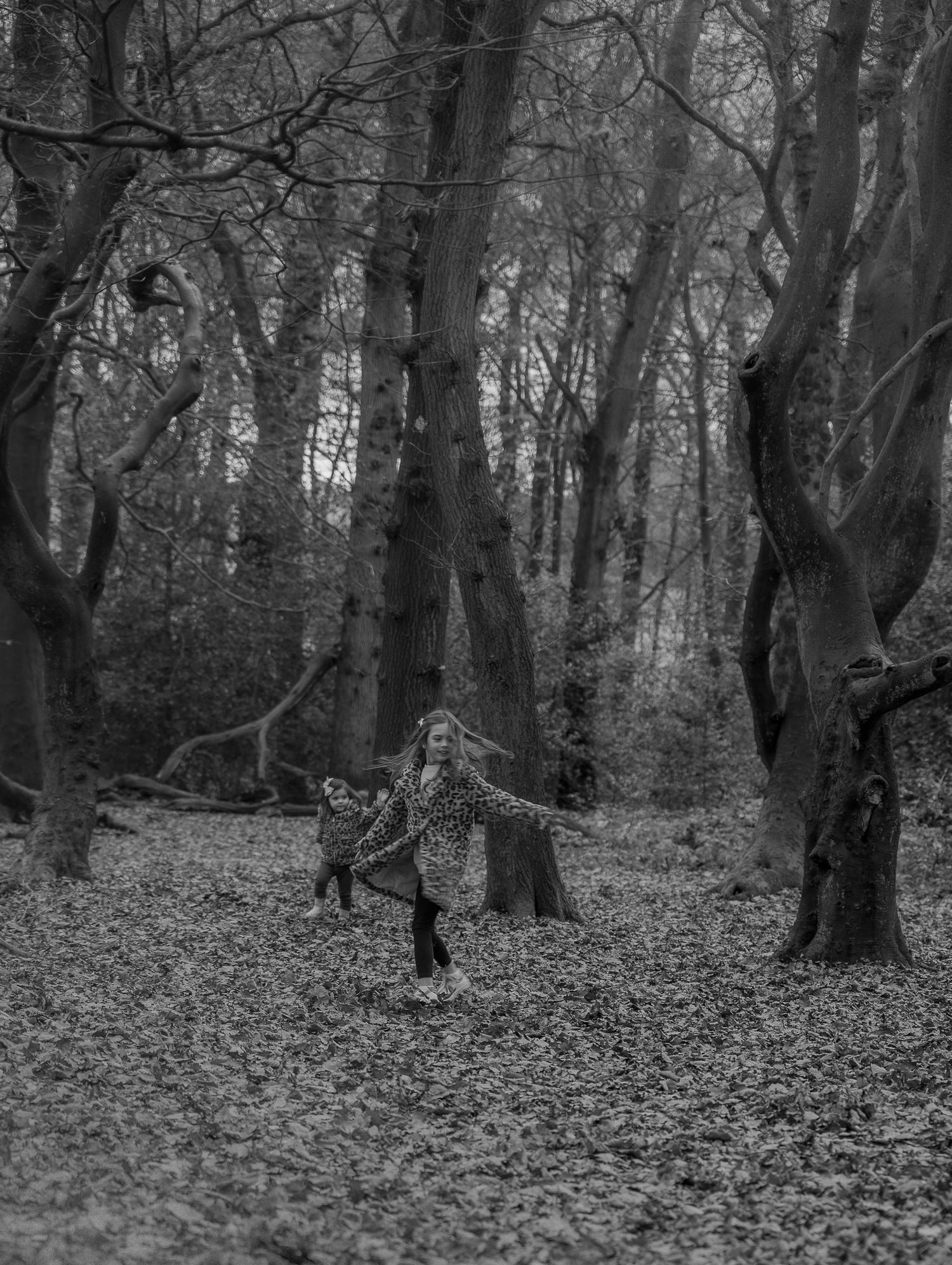Parents and children laughing together under golden autumn trees during lifestyle photoshoot.