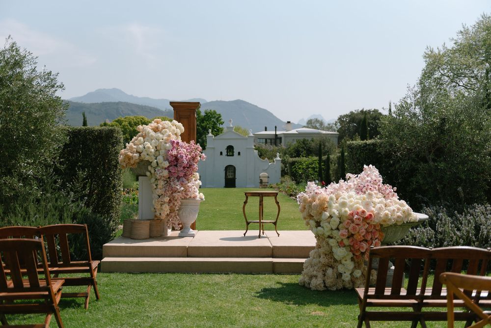 A panoramic view of a mountain landscape with wooden benches and pink flowering trees in a garden setting.