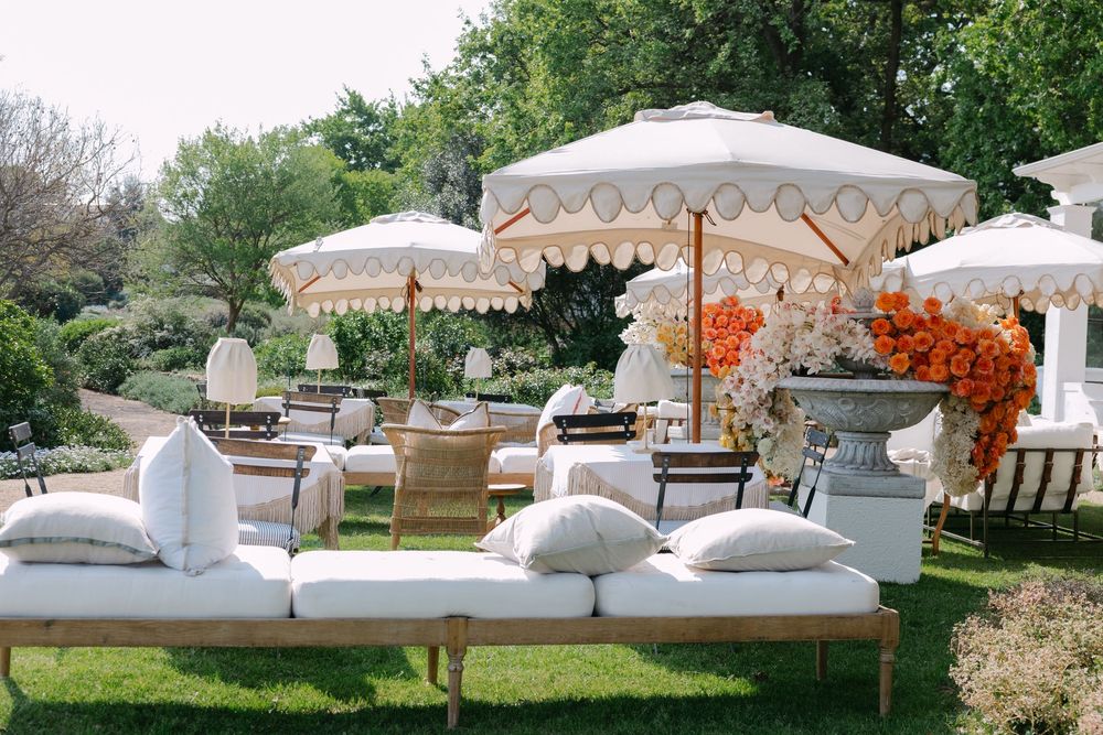 Elegant white lounge furniture and umbrellas arranged outdoors for a luxurious event setup.
