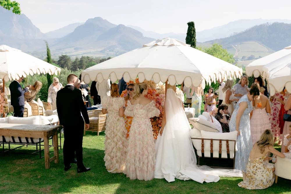 Outdoor wedding reception setup with white tents and mountain views in the background.