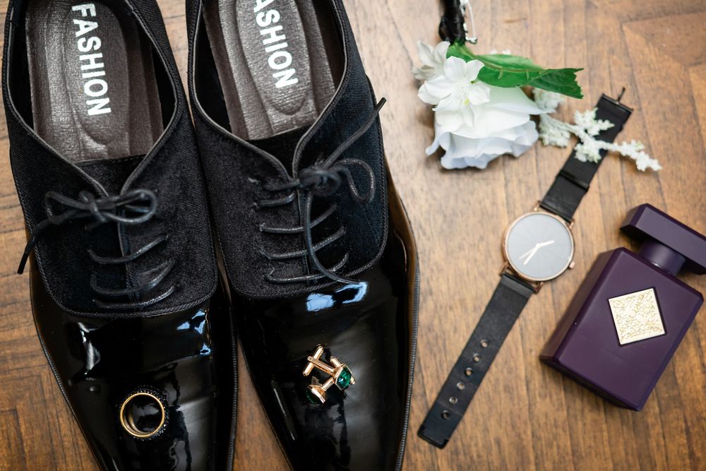 A collection of black leather dress shoes and boots arranged in a row on a wooden surface.