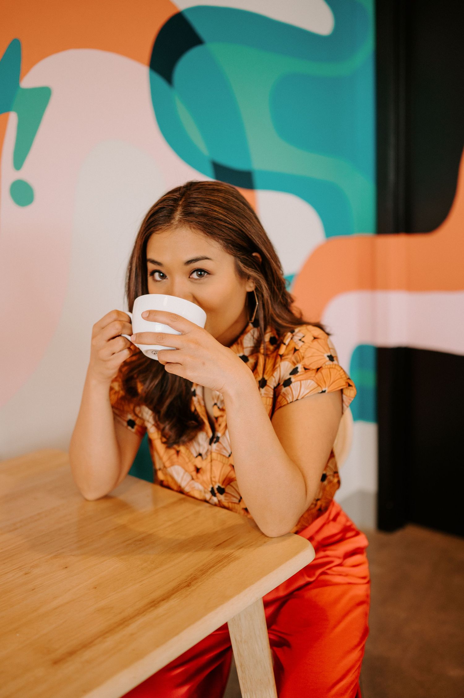 A playful scene at a wooden table with colorful abstract wall art in the background.