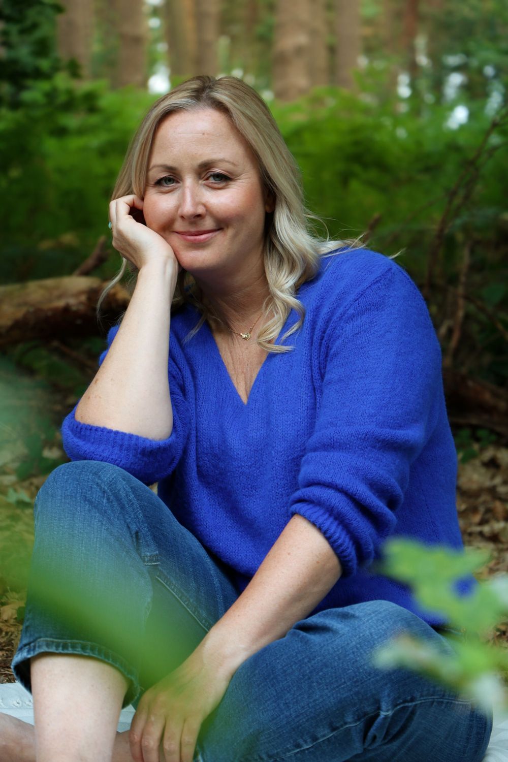 A person in a bright blue sweater sits outdoors against a natural green backdrop in a casual photo series.